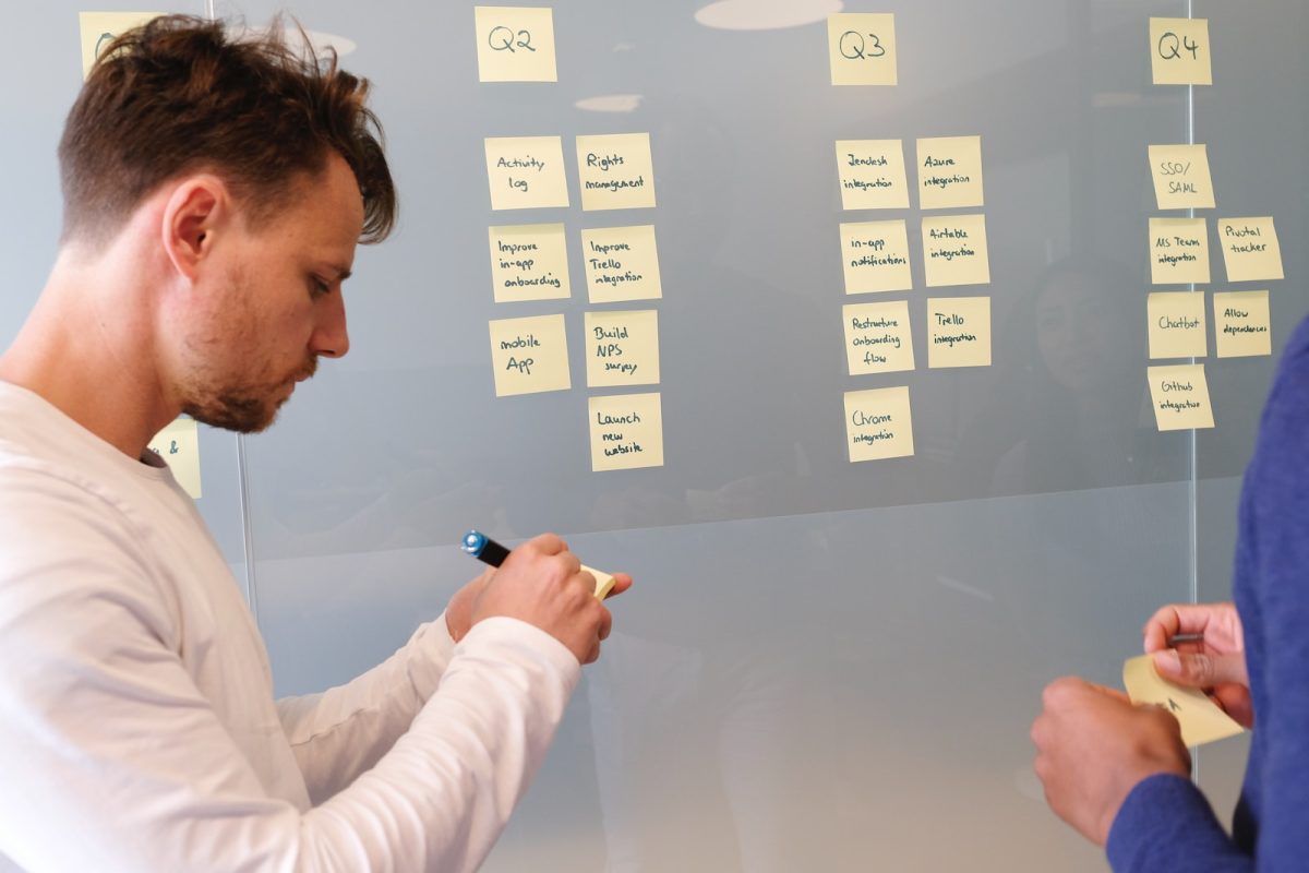 man in white long sleeve shirt writing on white board